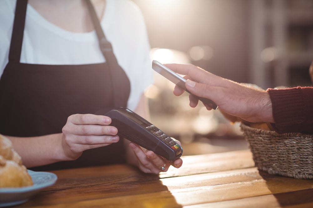 Customer paying bill through smartphone using NFC technology in cafe